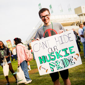 Student holding sign that reads "Can't hide our Huskie pride"