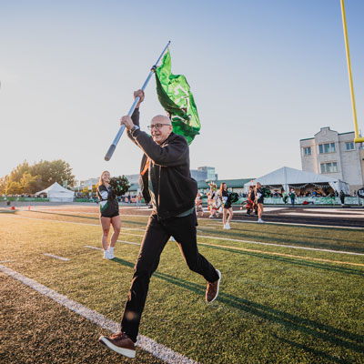 USask chancellor running flag on to the field